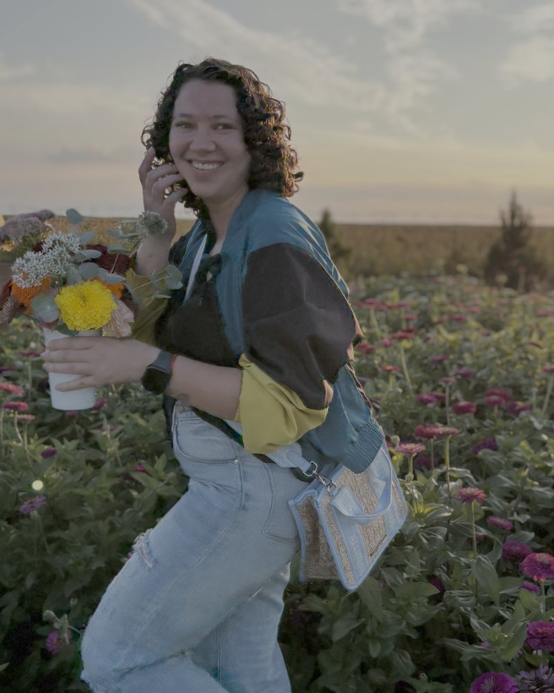 Ale, founder of StriveGrowth Solutions, smiling in a flower field at sunset